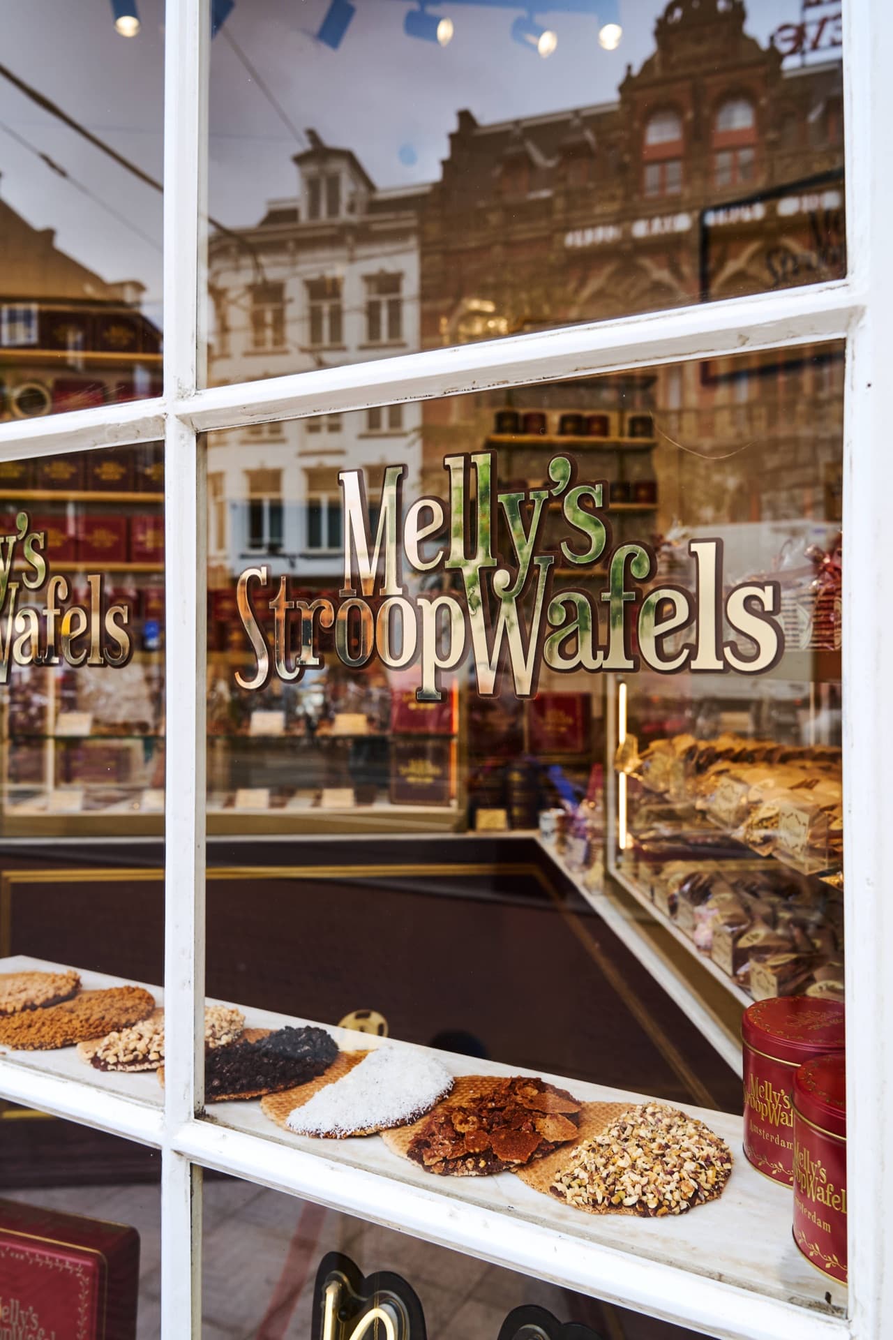 Melly's Stroopwafels shop window in central Amsterdam, with the gold sign and a row of freshly topped stroopwafels and gift tins